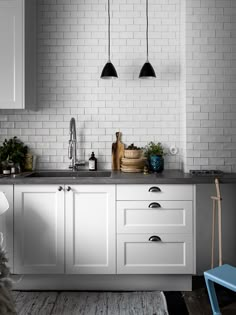 a kitchen with white cabinets and black pendant lights