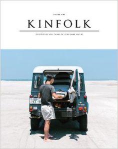 a man standing in the back of a green van on top of a sandy beach