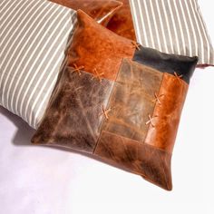 two brown and white pillows on top of each other next to striped pillowcases