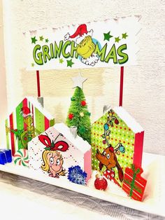 christmas presents are on display in front of a grinch - mas sign and tree