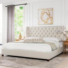 a large white bed sitting in a bedroom next to a dresser and lamp on top of a rug