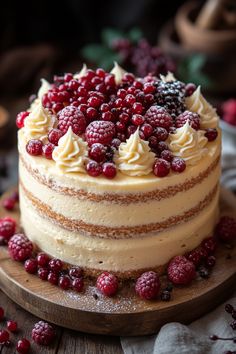 a cake with raspberries and cream frosting on a wooden board next to berries