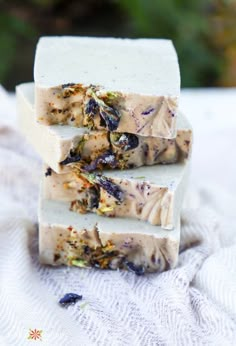 three soap bars stacked on top of each other with dried flowers in the middle and one bar cut off