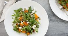 two white plates topped with salad next to silverware