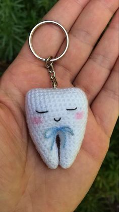 a crocheted tooth keychain is shown in someone's hand