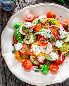 a white plate topped with lots of veggies on top of a wooden table