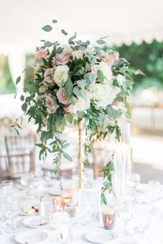 an elegant table setting with white and pink flowers in tall vases on the centerpiece