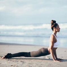 a woman is doing yoga on the beach