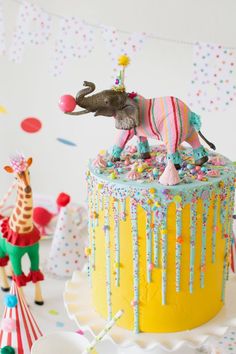 a birthday cake decorated with an elephant and giraffe figurine on top