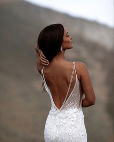 a woman in a white wedding dress looking off into the distance with her back to the camera