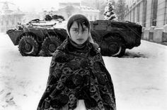 a woman standing in the snow next to tanks