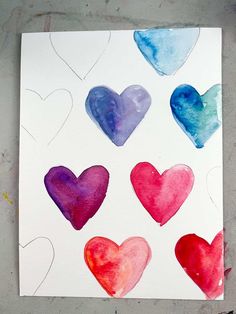 watercolor hearts painted on white paper with blue, red and pink colors in the middle