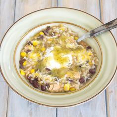 a bowl filled with rice and beans on top of a wooden table next to a spoon