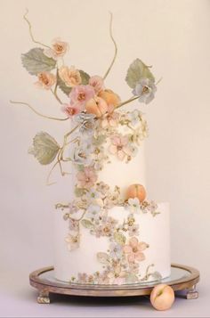 a three tiered white cake with flowers and leaves