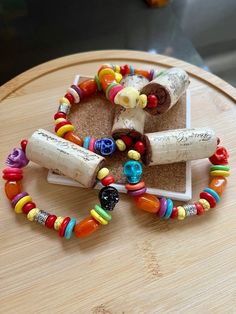 several bracelets made out of wine corks and colorful beads on a wooden table