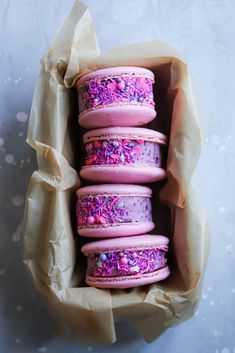 pink and purple macaroons with sprinkles in a box