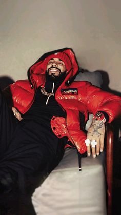 a man in a red jacket sitting on a bed