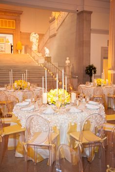 the tables are set with white and yellow linens for an elegant wedding reception at the grand staircase