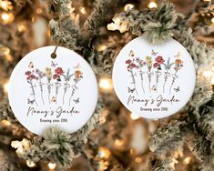 two personalized christmas ornaments hanging from a tree with lights in the background, one is for mom's garden and the other is for mommy's garden