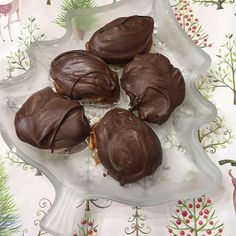 four chocolate covered pastries on a glass platter