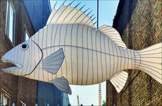 a large white fish hanging from the side of a building next to a brick wall