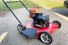 a red lawn mower sitting on top of a gravel road