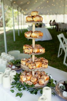 a table topped with lots of pastries on top of a white table covered in greenery