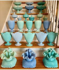 blue and green vases sitting on top of a set of wooden steps in front of a banister