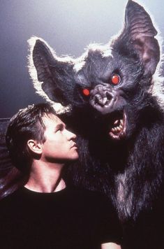 a man standing next to a demon with red eyes