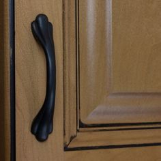 a black handle on a wooden cabinet door