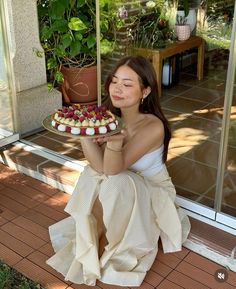 a woman sitting on the ground holding a cake