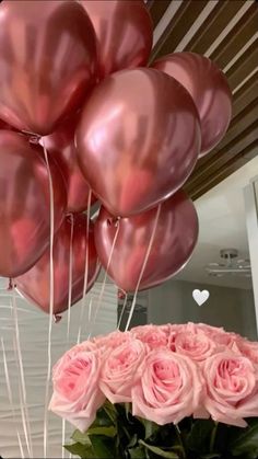 some pink roses are in a vase with balloons