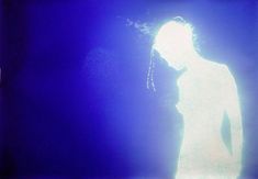 a man with dreadlocks standing in front of a blue background