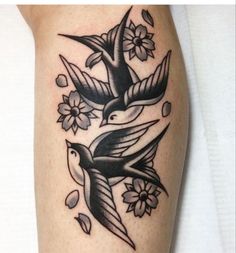 a tattoo with two birds and flowers on the arm, one is black and white