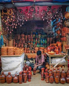 a man sitting in front of a store filled with pottery