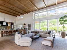 a living room filled with furniture next to large windows and lots of wooden flooring