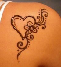 the back of a woman's shoulder with a heart and flower tattoo on it