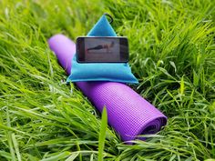 a purple yoga mat laying in the grass with a cell phone on top of it