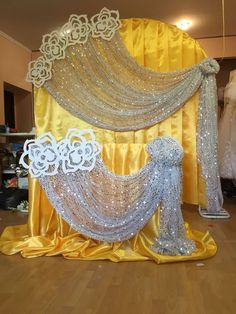 an elaborately decorated stage set up with gold and silver drapes, white flowers, and lace