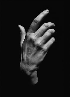 black and white photograph of a person's hand holding something in the air with their fingers