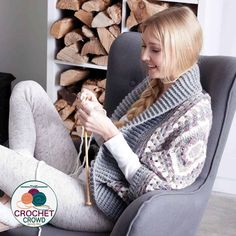 a woman sitting in a chair with her legs crossed and holding a crochet hook