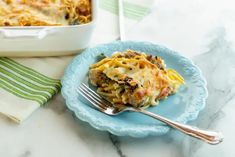 a blue plate topped with lasagna next to a casserole dish