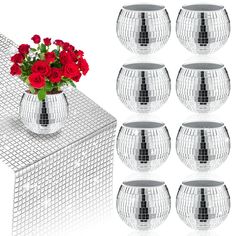 a bunch of red roses are in a vase on a white table with silver mesh