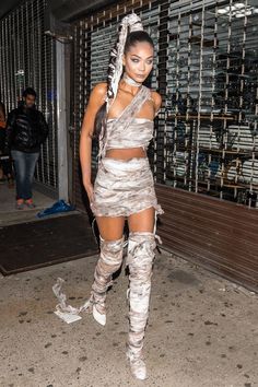 a woman in silver dress and boots walking down the street