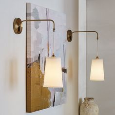 two lamps are hanging on the wall next to a vase