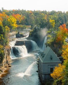 a view of a waterfall in the middle of a forest with fall foliage around it