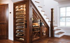 a wine cellar in the corner of a room with stairs leading up to an open door