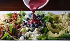 a salad with blueberries and avocado is being drizzled with ketchup