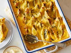 a casserole dish with cheese and spinach in it next to a bowl of soup