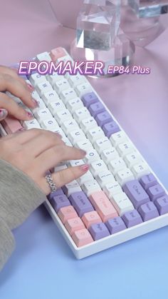 a woman is typing on a keyboard with pink and purple keys in front of her